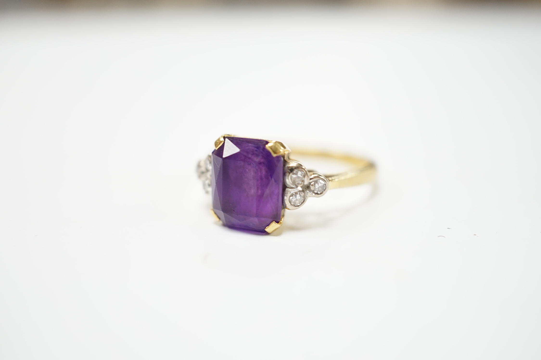 An 18ct and single stone emerald cut amethyst set ring with diamond set shoulders, size M, gross weight 4.5 grams.